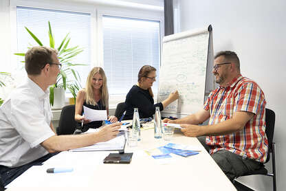 Team des Pflegereferats, bestehend aus 4 Personen, sitzt gut gelaunt an einem Tisch, Frau Esther Braun schreibt etwas auf ein Flipchart