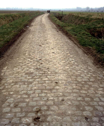 Ein gepflasterter Web in einem Feld, der in die Ferne führt