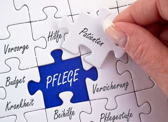 Puzzel, ein Puzzel in blau mit dem Wort "Pflege", die anderen mit weiteren Pflegebegriffen